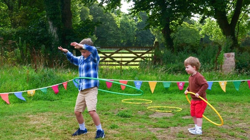 An image of two children hula hooping in the field at Trerice as part of their Summer of Play activities